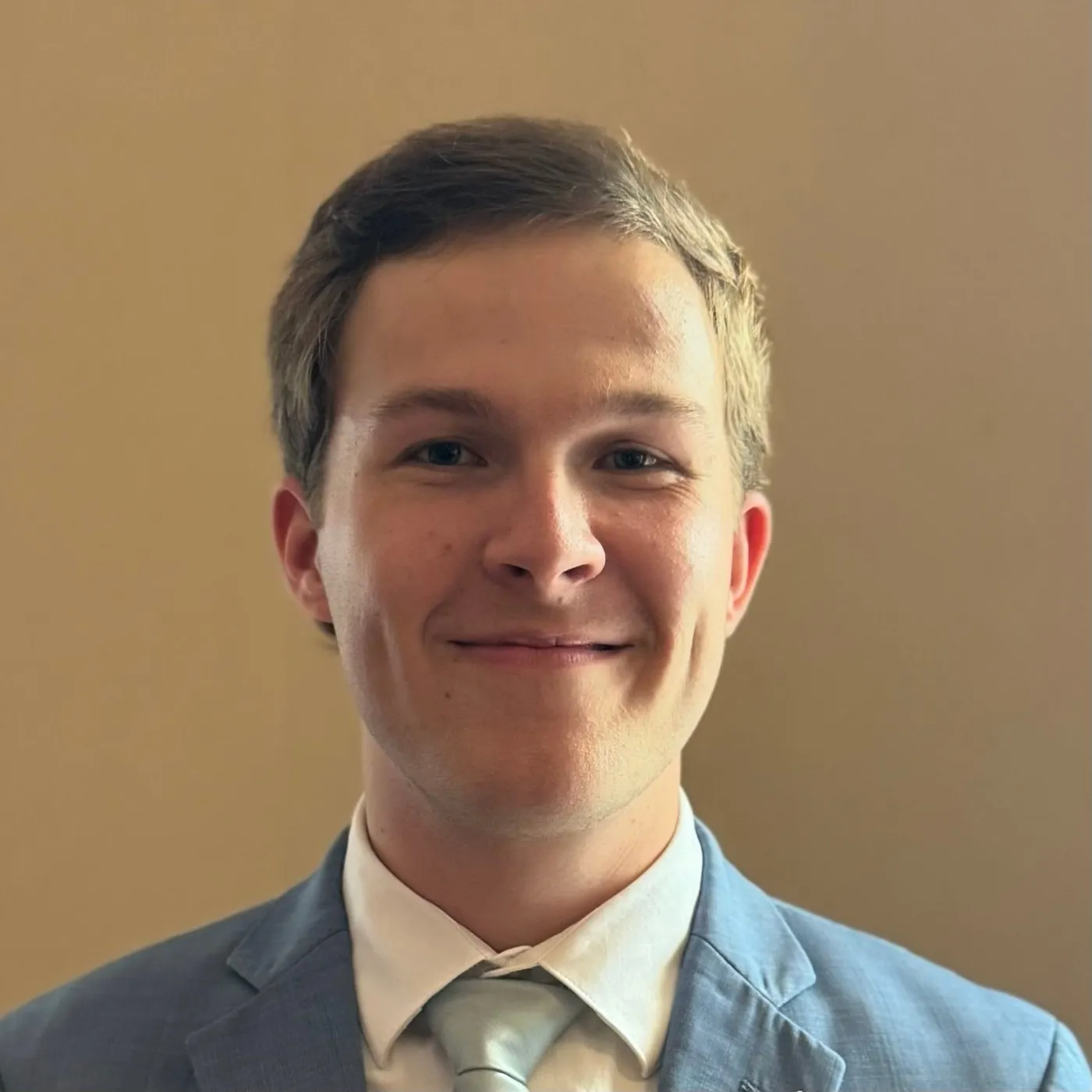 Headshot of Justin Reini in a light blue suit and tie.
